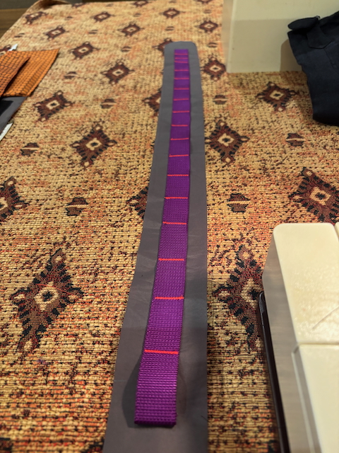 The bottom panel with webbing attached using lots of crude bar tacks of short zig-zag stitches.